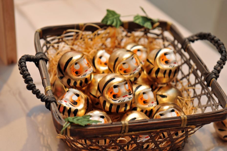 A selection of small golden Daruma dolls in a basket.
