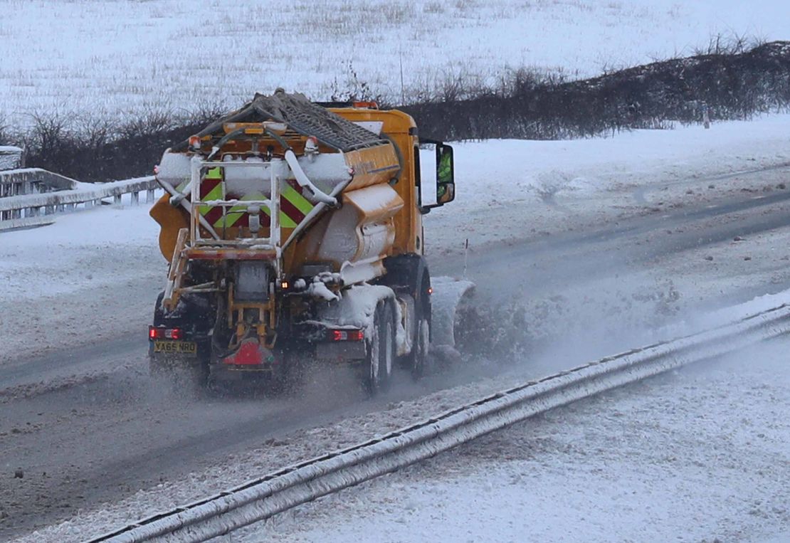 A snow plow spreads grit and clears the M9 motorway in Scotland.