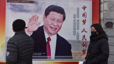 People walk past a poster of Chinese President Xi Jinping beside a street in Beijing on February 26, 2018.