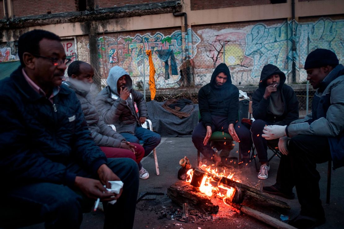 Migrants warm up around a fire at a makeshift camp in Rome in February.