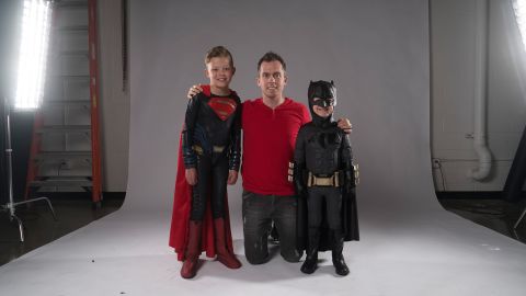 Digital artist and photographer Josh Rossi posing with nine-year-old Teagan Pettit as Superman and five-year-old Simon Fullmer as Batman.