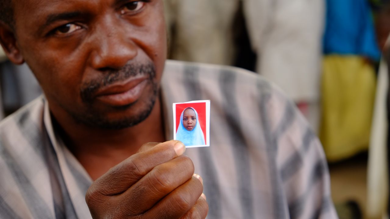 Alhaji Garba Tela shows a photograph of his missing daughter, Zainab.