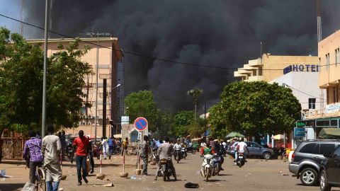 People watch as black smoke rises in the capital of Burkina Faso after it came under attack Friday.