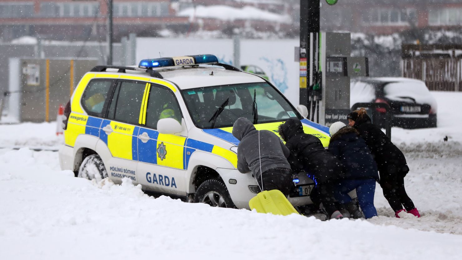 People help push a stranded Garda police car amid the snowfall in Ireland's Dublin area.