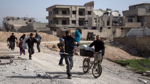 Syrians flee their homes with their belongings in the town of Beit Sawa in Syria's besieged eastern Ghouta region on March 4, 2018, following reported air strikes.