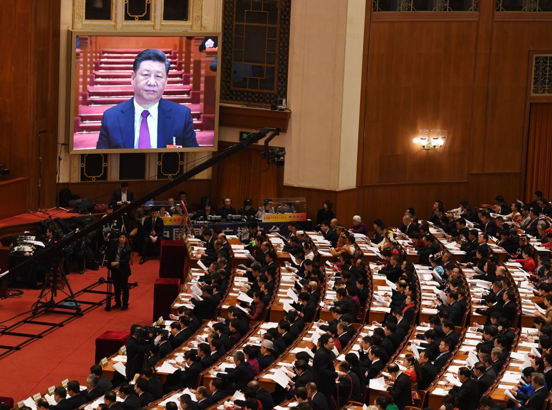 Chinese President Xi Jinping is seen on a screen above delegates  during the opening session of the National People's Congress in the Great Hall of the People in Beijing on March 5, 2018.
