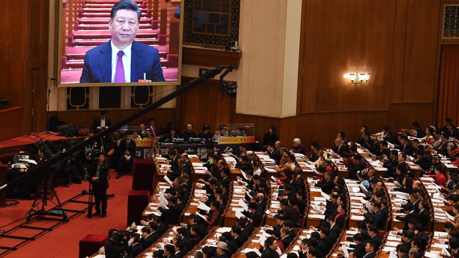 A live image of Chinese President Xi Jinping is seen on a screen above delegates during the opening session of the National People's Congress in the Great Hall of the People in Beijing on March 5, 2018.