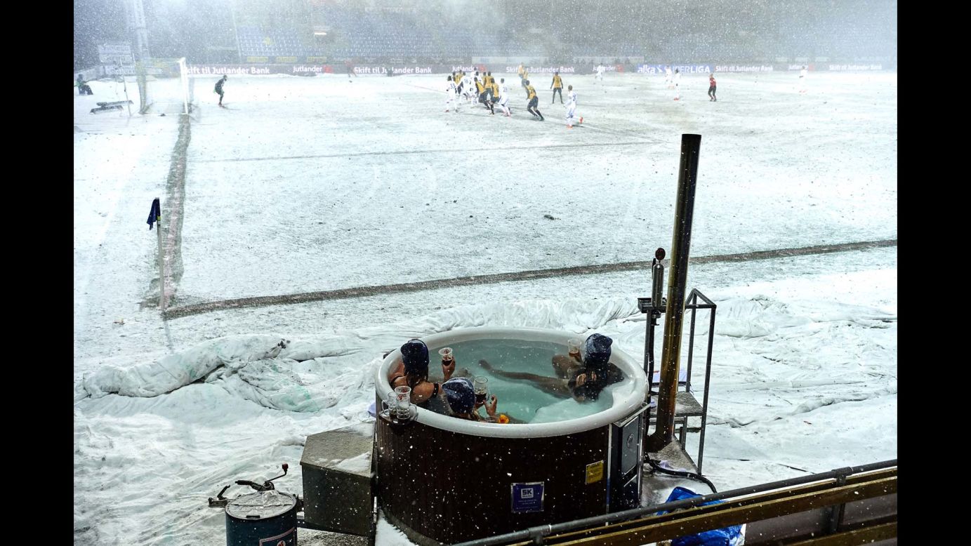 Soccer fans in Hobro, Denmark, watch a match from a hot tub on Wednesday, February 28. They won a contest to get their unique view.