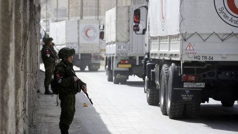 Russian soldiers stand guard as Syrian Arab Reb Crescent trucks carrying aid drive past on March 5.