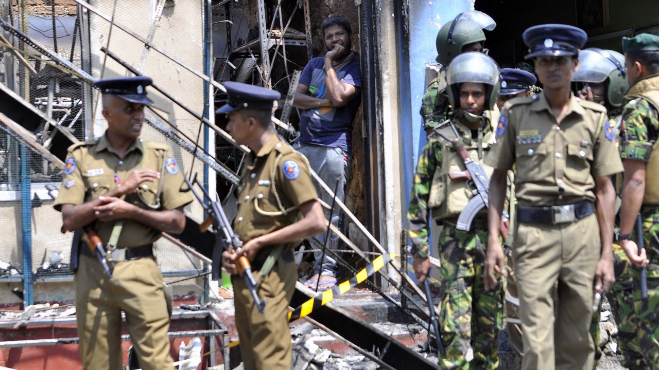 A man looks out from a burned-out home, as Sri Lankan police commandos patrol on the streets of Pallekele, a suburb of Kandy, on March 6, 2018.