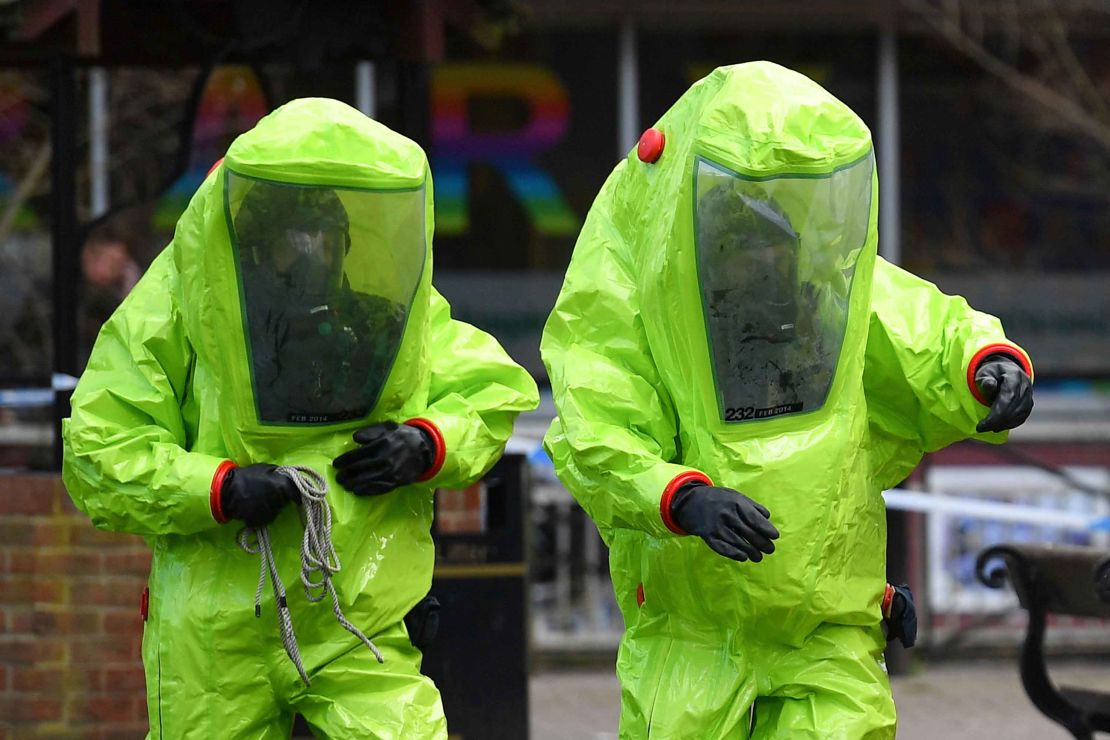 Members of the emergency services in green biohazard suits work to afix the tent over the bench where Sergei Skripal and his daughter Yulia were found.