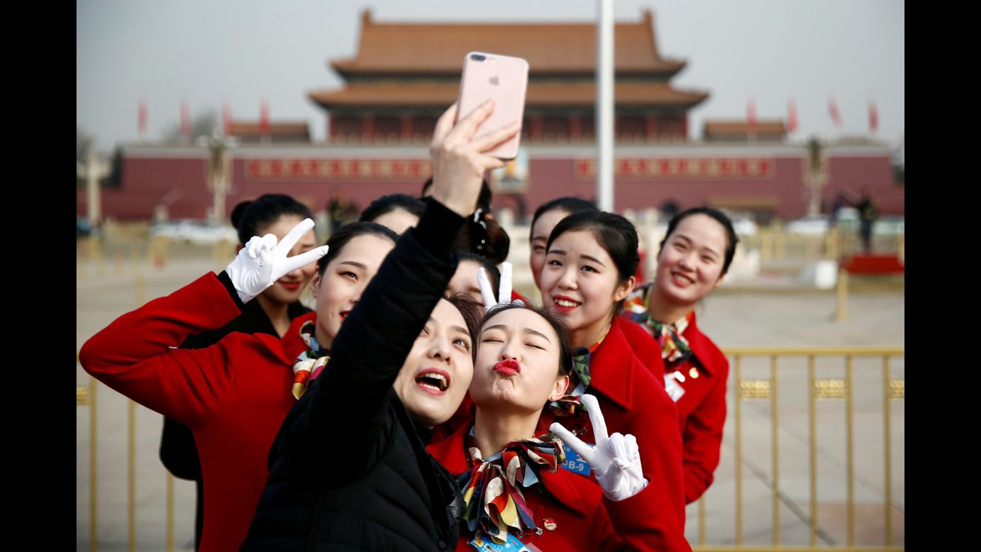Ushers pose for pictures in Beijing's Tiananmen Square on Monday, March 5. It was during the opening session of the National People's Congress.
