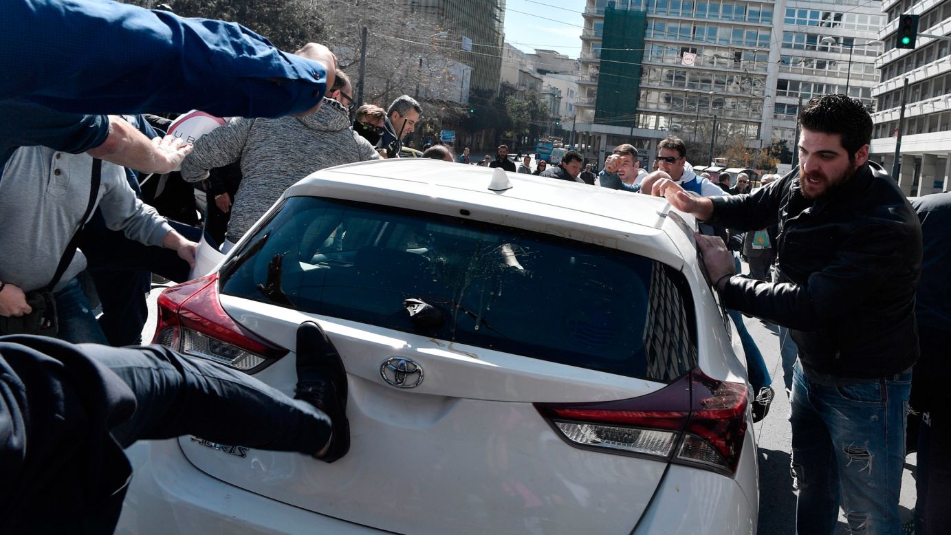 Taxi drivers attack an Uber driver's vehicle during a protest in Athens, Greece, on Tuesday, March 6. Taxi driver unions have complained that Uber is unfair competition.