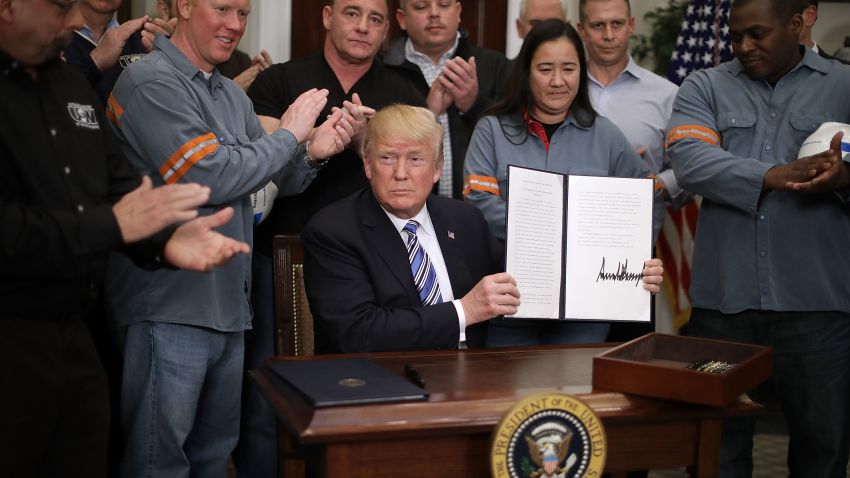 WASHINGTON, DC - MARCH 08:  Surrounded by applauding steel and aluminum workers, U.S. President Donald Trump holds up the 'Section 232 Proclamations' on steel imports that he signed in Roosevelt Room the the White House March 8, 2018 in Washington, DC. Trump announced last week that he will put a 25-percent tarriff on imported steel and a 10-percent tarriff on imported alumninum.  (Photo by Chip Somodevilla/Getty Images)