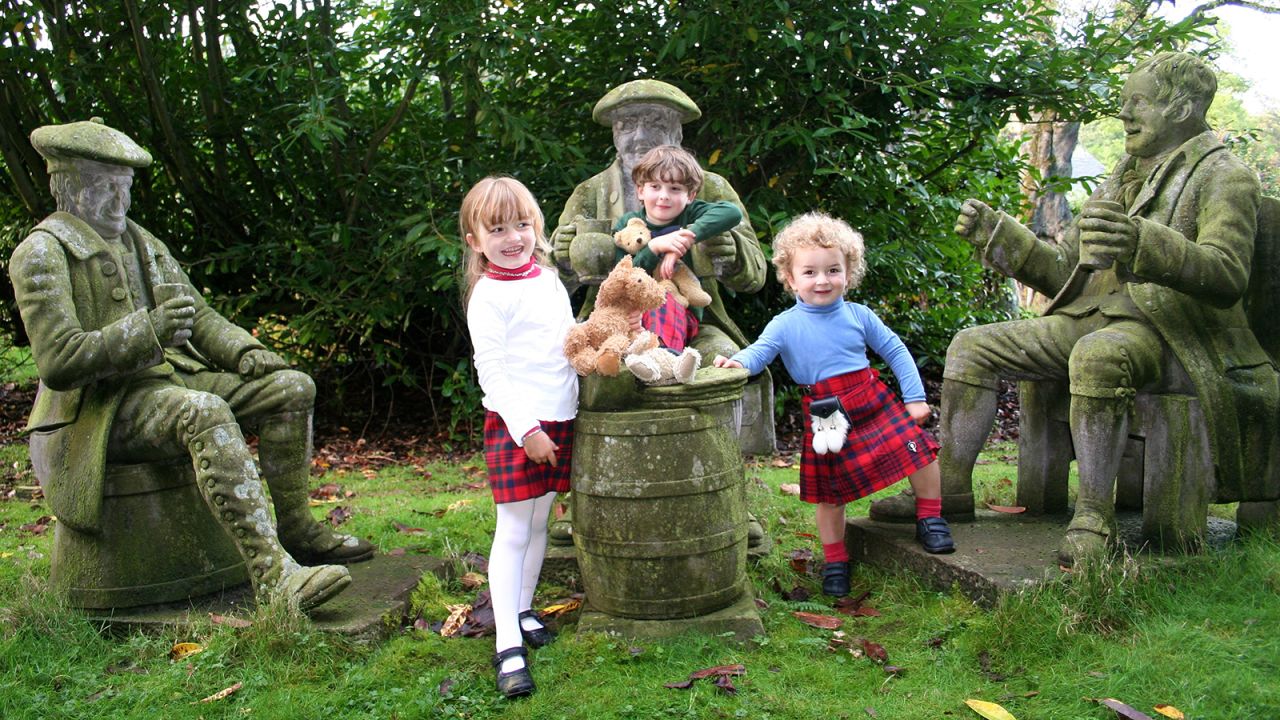 The Threipland's three children Peter, Beatrice and Sacha (now aged 17, 16 and 13 respectively) in the garden of Fingask Castle. The garden contains a collection of life-sized statues that were installed by Andrew Threipland's ancestor, Sir Peter Threipland, in the mid 19th century. Most are characters from Scottish literature. Robert Burns, the Scottish poet and lyricist, is seated on the right with his literary creations, Tam O'Shanter and Souter Johnnie, next to him.   