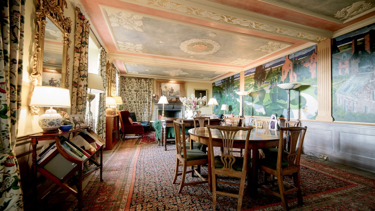 Fingask Castle's dining room, where the family eats dinner. Along the walls are murals of the castle and gardens.