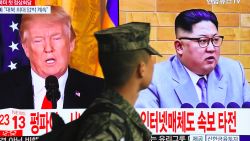 TOPSHOT - A South Korean soldier walks past a television screen showing pictures of US President Donald Trump (L) and North Korean leader Kim Jong Un at a railway station in Seoul on March 9, 2018.