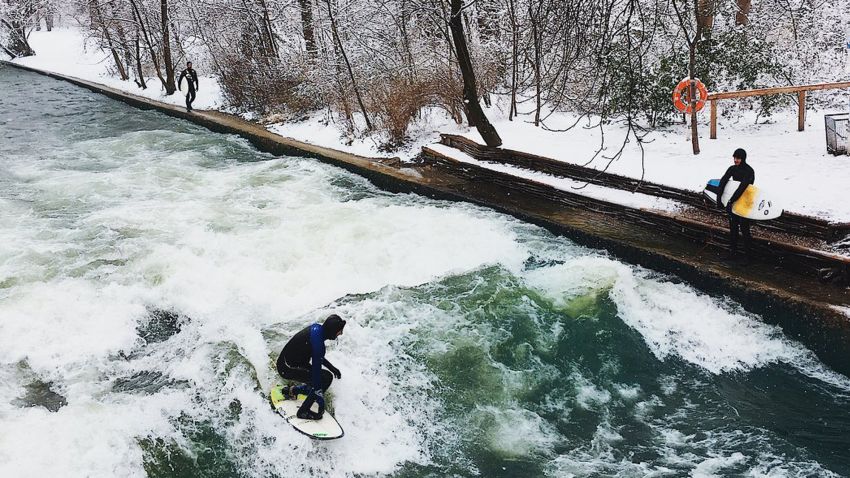 Surfers ride the waves at the Eisbach Welle in Munich, Germany