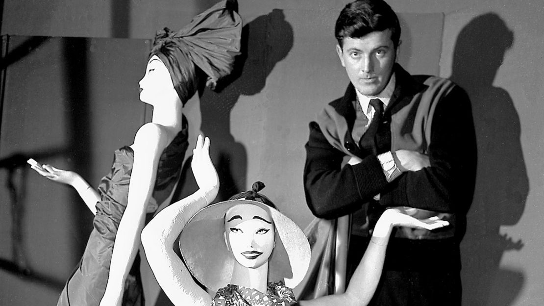 In this 1952 file photo, French fashion designer Hubert de Givenchy poses with mannequins in his shop in Paris.