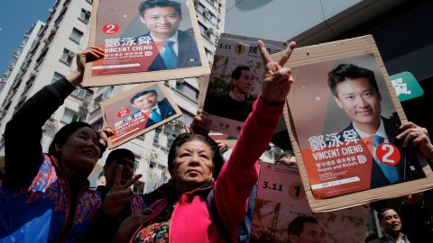 Supporters of Hong Kong pro-Beijing by-election candidate Vincent Cheng Wing-shun wave posters during an election campaign in Hong Kong, Sunday, March 11.