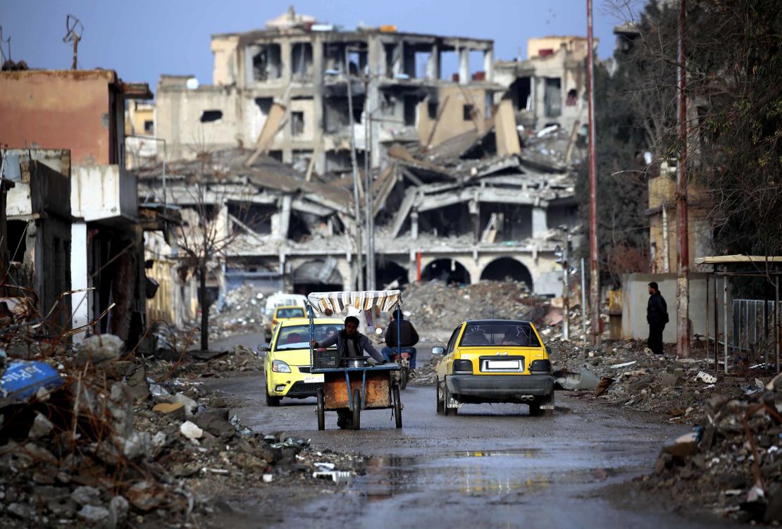 Syrians make their way along a destroyed street in Raqqa, on February 18, 2018. 