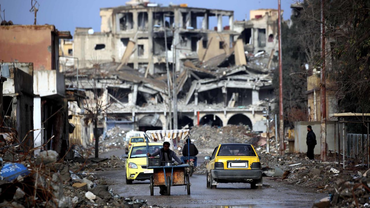 Syrians make their way along a destroyed street in Raqqa, on February 18, 2018.