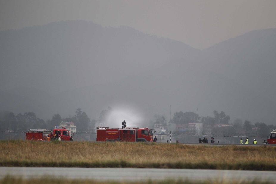 Fire trucks work to extinguish the plane's smoldering wreckage.