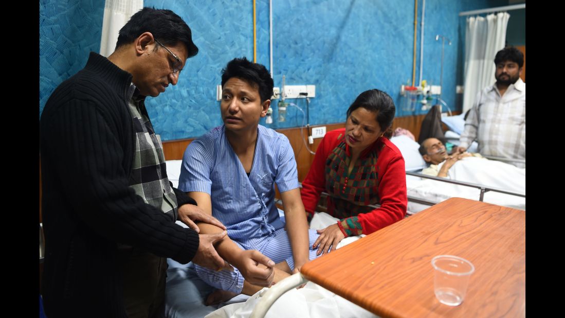 Plane crash survivor Sanam Shakya, center, talks with his parents at a hospital in Kathmandu.