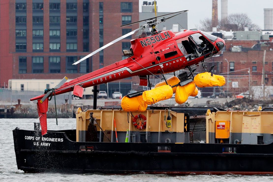 A helicopter is hoisted by crane from the East River onto a barge, Monday, March 12, 2018, in New York.