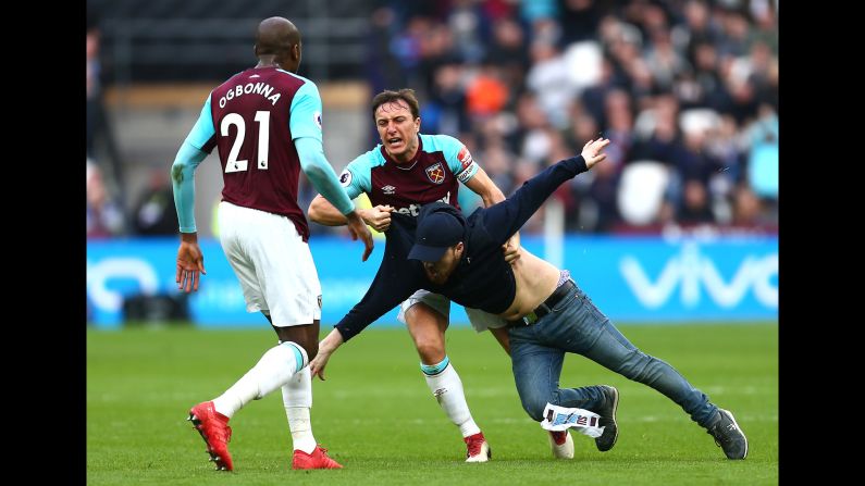 West Ham captain Mark Noble clashes with one of several disgruntled supporters <a href="index.php?page=&url=http%3A%2F%2Fbleacherreport.com%2Farticles%2F2763661-west-ham-fans-invade-pitch-confront-players-during-loss-vs-burnley" target="_blank" target="_blank">who ran onto the field</a> during the London club's 3-0 loss to Burnley on Saturday, March 10.