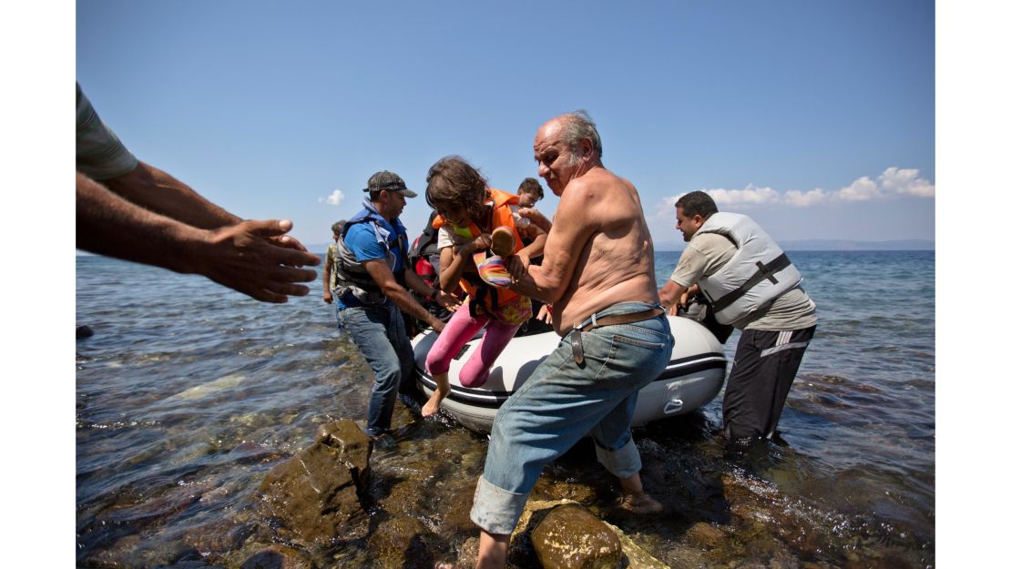 A local helps a Syrian migrant child upon their arrival on a dinghy in the village of Sikaminies, at the southeastern Greek island of Lesbos, Greece.