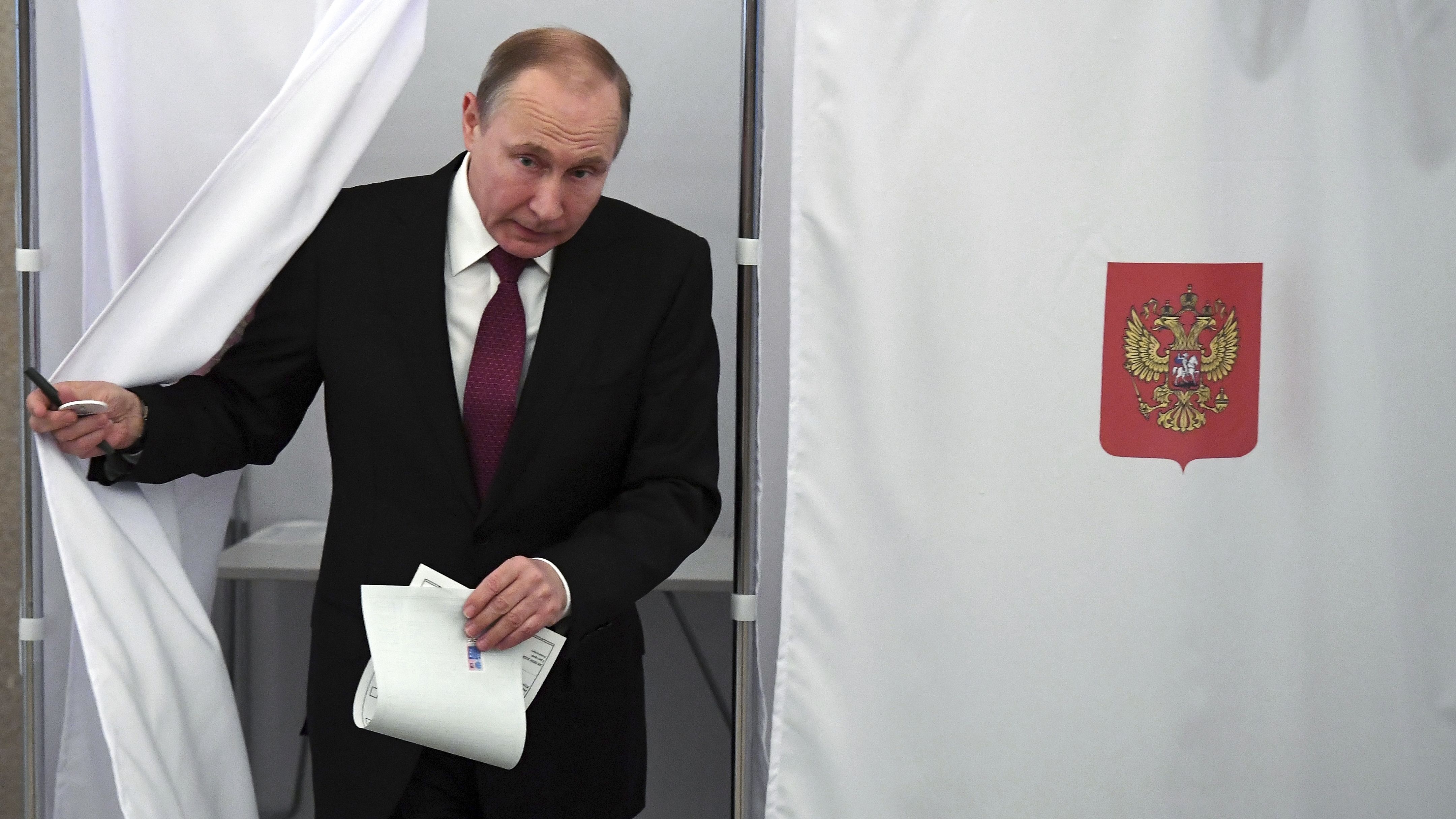 Russian President Vladimir Putin exits a polling booth as he prepares to cast his ballot during Russia's presidential election. 