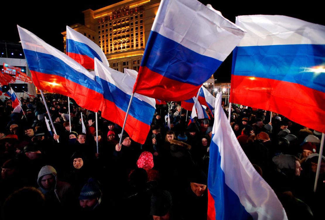 People wave Russian flags in Manezhnaya Square near the Kremlin on Sunday.