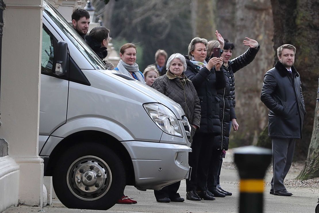 People wave to others aboard diplomatic vehicles leaving the Russian Embassy.