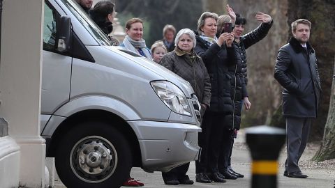 People wave to others aboard diplomatic vehicles leaving the Russian Embassy.