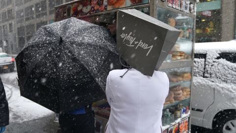 A Lord & Taylor employee takes cover from snow Wednesday on Fifth Avenue in New York.