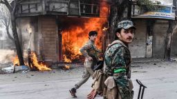 Turkish-backed Syrian rebels walk past a burning shop in the city of Afrin in northern Syria on March 18, 2018.Turkish forces and their rebel allies were in control of the Kurdish-majority city of Afrin in northwestern Syria, AFP journalists on the ground reported. / AFP PHOTO / Bulent Kilic        (Photo credit should read BULENT KILIC/AFP/Getty Images)