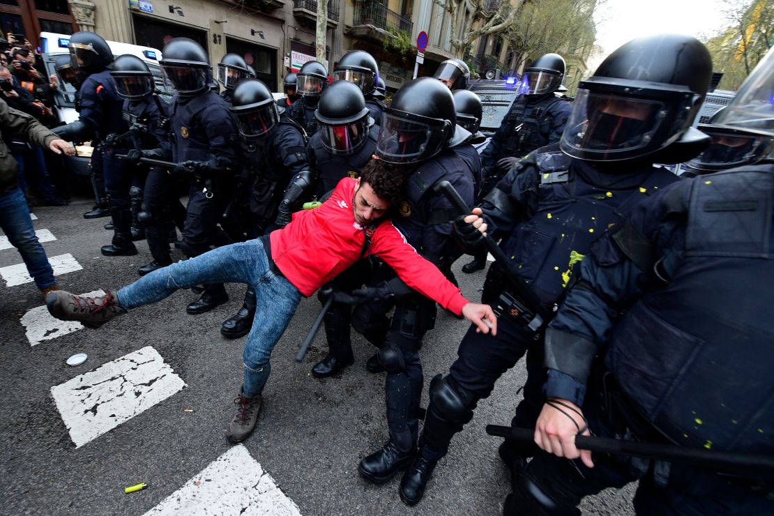 A protester is pulled by riot police blocking the road leading to the central government in Barcelona on March 25, 2018.