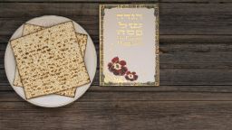 White plate  with matzah or matza and Passover Haggadah on a vintage wood background presented as a Passover seder feast or meal with copy space. Perfect for your Passover design.