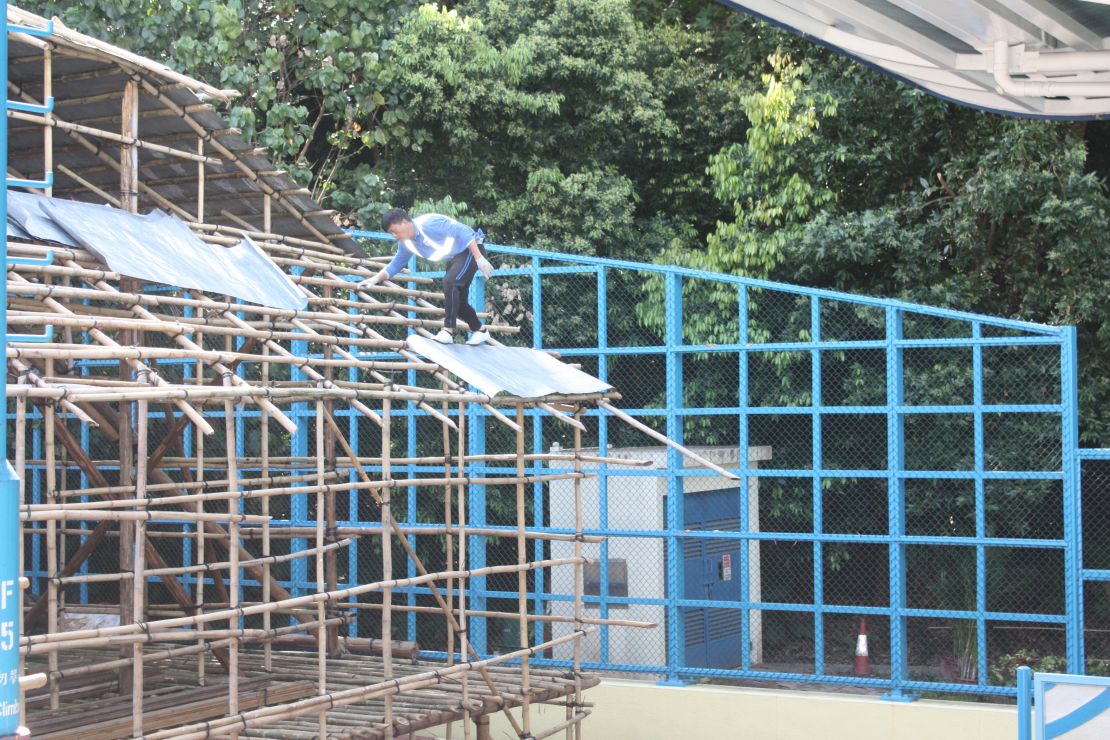 A worker scales the bamboo grid.