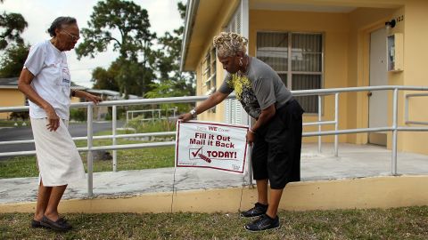 Census volunteer Gail Alexander places a sign in front of the home of Sarah McCloud as they visit homes during the "March to the Mailbox" effort on April 10, 2010 in Miami, Florida. (Photo by Joe Raedle/Getty Images)