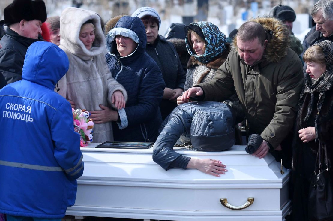 People mourn over a coffin during a funeral in Kemerovo.