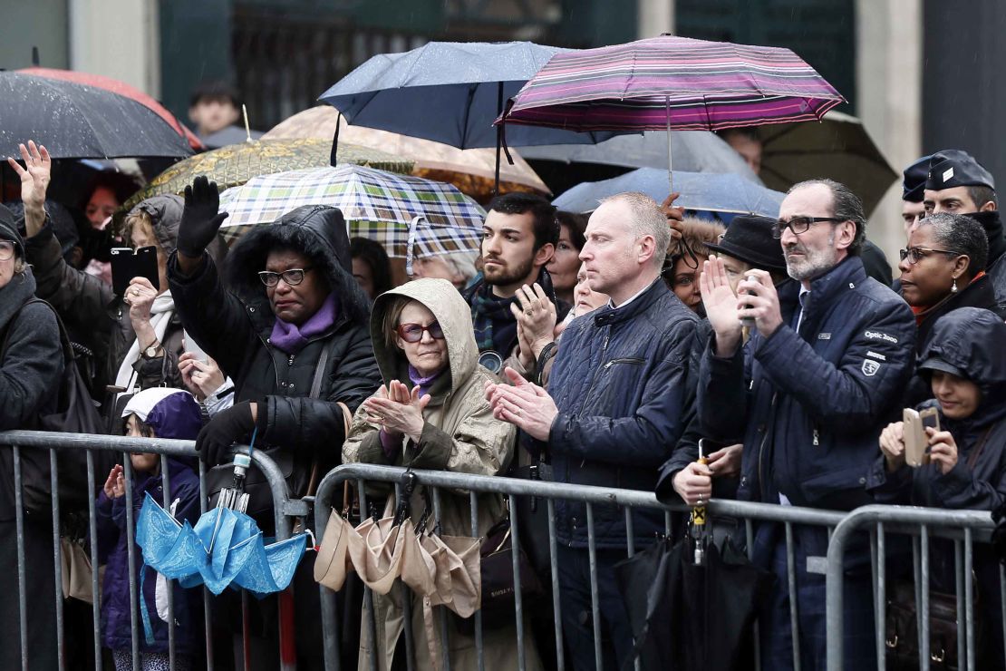 People applaud while Beltrame's coffin passes in central Paris.  