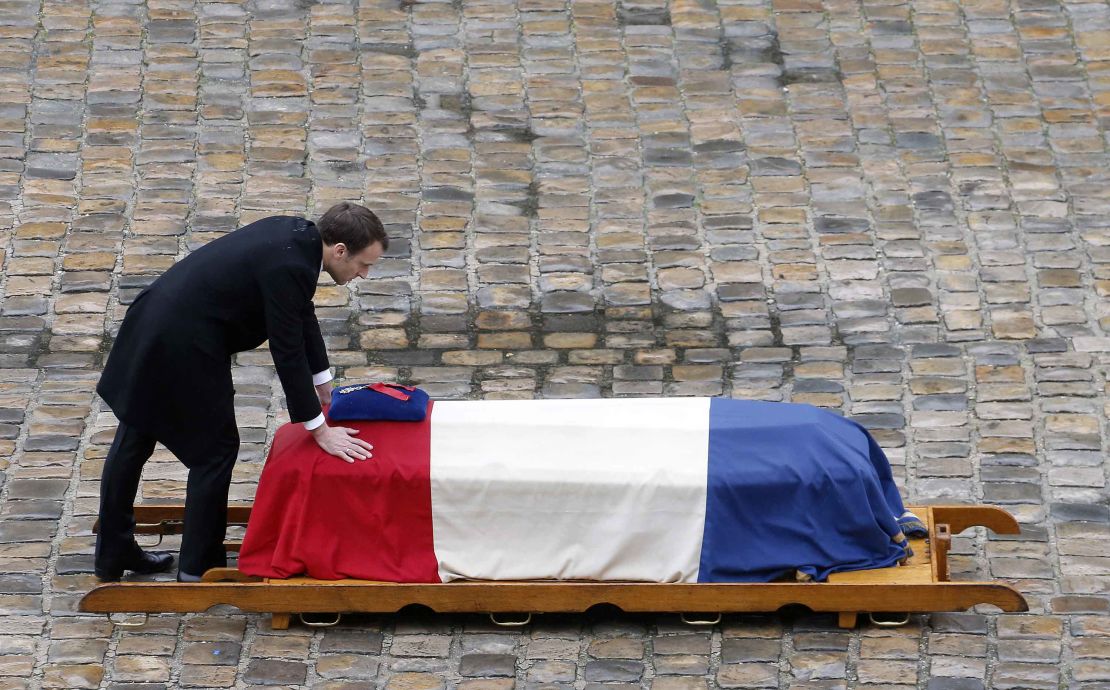 French President Emmanuel Macron touches the flag-draped coffin of Arnaud Beltrame.