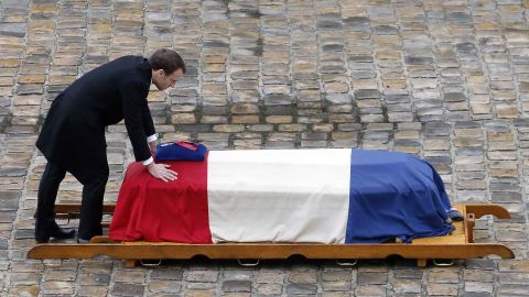 French President Emmanuel Macron touches the flag-draped coffin of Arnaud Beltrame.