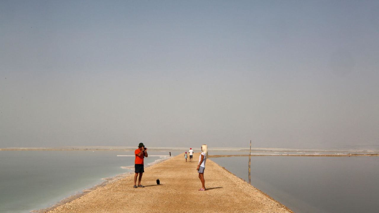 <strong>Neve Zohar, Israel: </strong>Tourists pose for pictures on an embankment between evaporation ponds -- used to remove salt from the water -- in the southern part of the Dead Sea in community settlement Neve Zohar. 