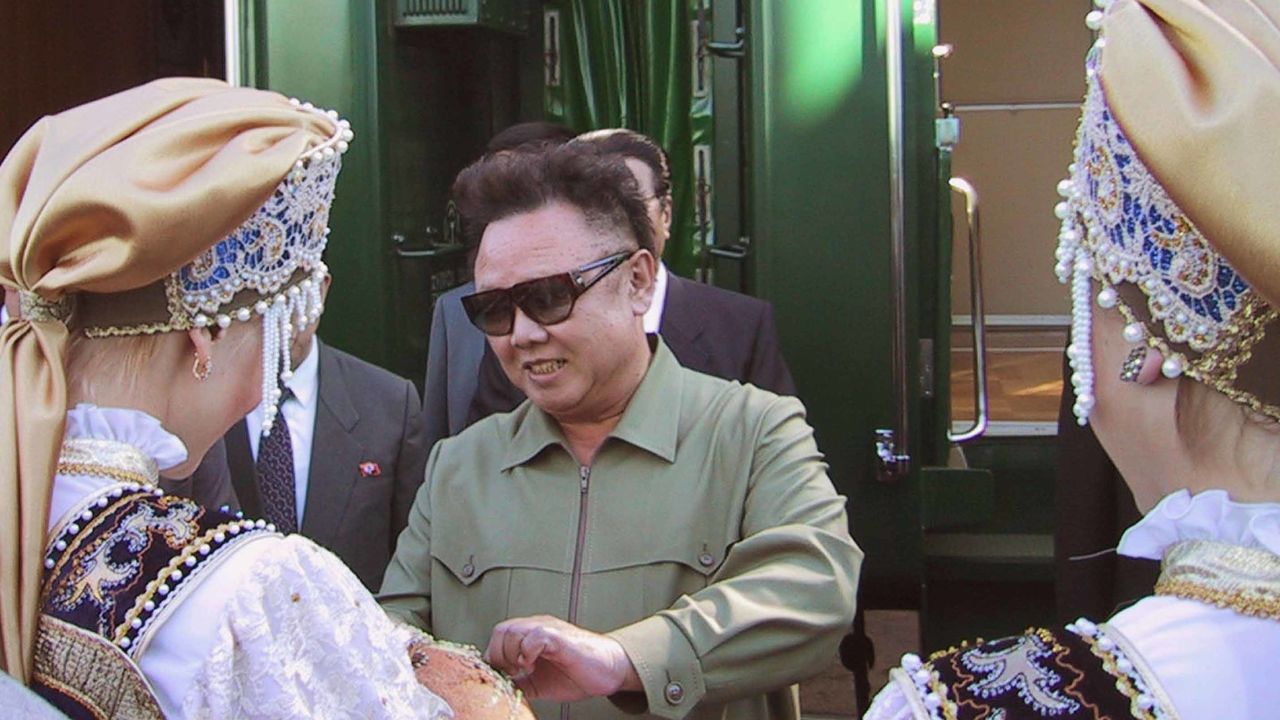 Kim Jong Un's father, Kim Jong Il,  is greeted by women in traditional costume as he arrives in Omsk, Russia in 2001.