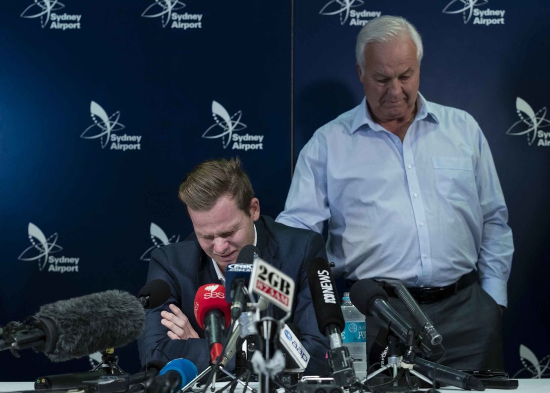 An emotional Steve Smith is comforted by his father Peter as he fronts the media at Sydney International Airport.