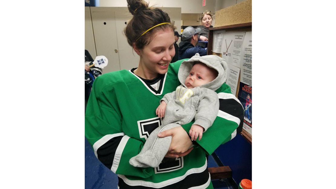 Serah Small holds her 8-week old baby, Ellie, while wearing her hockey uniform.