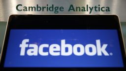 A laptop showing the Facebook logo is held alongside a Cambridge Analytica sign at the entrance to the building housing the offices of Cambridge Analytica, in central London on March 21, 2018. 
Facebook expressed outrage over the misuse of its data as Cambridge Analytica, the British firm at the centre of a major scandal rocking the social media giant, suspended its chief executive.  / AFP PHOTO / Daniel LEAL-OLIVAS        (Photo credit should read DANIEL LEAL-OLIVAS/AFP/Getty Images)